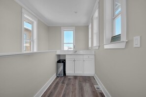 Un pasillo estrecho con una zona de cocina que incluye armarios blancos, una estufa de acero inoxidable y una ventana con vistas.