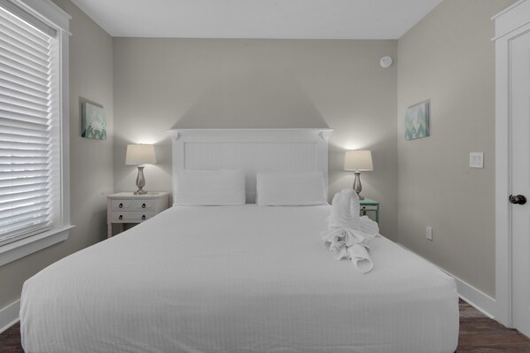 Une chambre à coucher bien rangée, avec un grand lit, deux tables de chevet dotées de lampes et une porte.