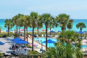 A pool area with palm trees, sun loungers, and umbrellas. - Dunes Of Panama B208 (Panama City Beach)