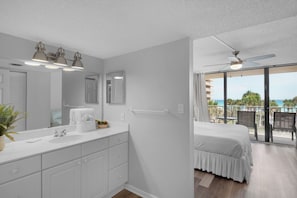 A modern hotel room with a large balcony, a ceiling fan, and a view of the ocean. - Dunes Of Panama B208 (Panama City Beach)