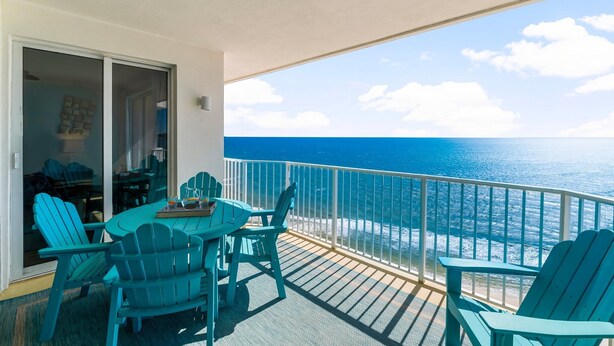 Ein Balkon mit Meerblick, ausgestattet mit Tisch und Stühlen sowie einem kleinen Tisch mit einem Getränk.