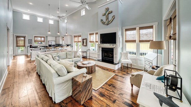 A spacious living room with a fireplace, a dining area, and a kitchen in the background. - Windmark Beach House | Walk to Beach | Pool & Pets (Port St Joe)