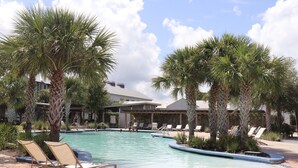 A swimming pool with lounge chairs and palm trees, surrounded by buildings. - Windmark Beach House | Walk to Beach | Pool & Pets (Port St Joe)