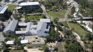 An aerial view of a resort with multiple buildings, a central swimming pool, and a beach in the background. - Windmark Beach House | Walk to Beach | Pool & Pets (Port St Joe)