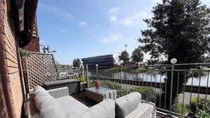 Un balcon agrémenté de meubles en osier, avec vue sur une rivière et une clôture en métal.