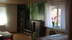 Een knus vertrek met een open haard, een eettafel en een raam met gordijnen.