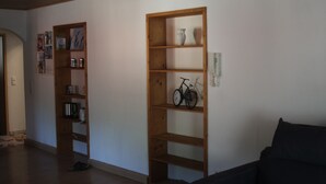 Een kamer met houten wandplanken, waarvan één boeken bevat en de andere een fiets en decoratieve objecten.