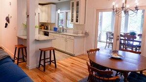 A modern kitchen with white cabinets, a wooden dining table, and a chandelier.