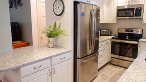 A modern kitchen with white cabinets, stainless steel appliances, and a granite countertop.