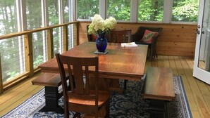 A wooden deck with a dining table, chairs, and benches.