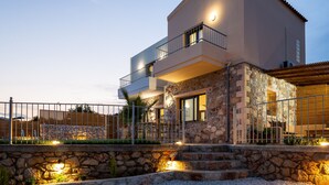 Een modern huis met twee verdiepingen, een stenen gevel, een balkon en buitenverlichting.