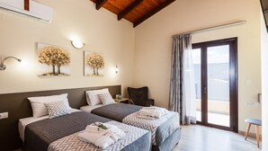 Een hotelkamer met twee bedden, een houten plafond, een balkon met uitzicht en kunstwerken aan de muren.