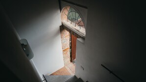 Una escalera que lleva a una habitación con ventana que da a un muro de ladrillos.