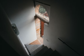 Un escalier menant à une pièce dotée d’une fenêtre donnant sur un mur de briques.