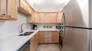 A modern kitchen with wooden cabinets, stainless steel appliances, and a white countertop. - Home At The Maya.... (Scottsdale)