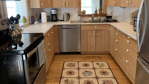 Een moderne keuken met houten kastjes, roestvrijstalen apparatuur en een betegelde vloer.
