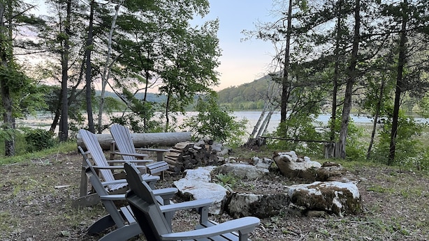 Een oeverlandschap met Adirondack stoelen en een houtvuur.