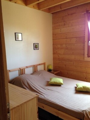 A single bed with a wooden headboard and footboard, two pillows, a bedside table with a lamp, and two framed pictures on the wall. - LOG HOME LA ROQUE GAGEAC LA SALAMANDRE 2 (La Roque-Gageac)