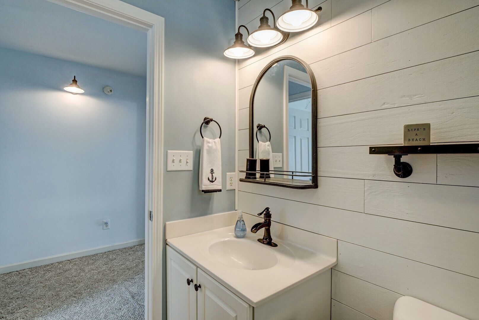 A bathroom with a white sink, a mirror, and a towel rack.
