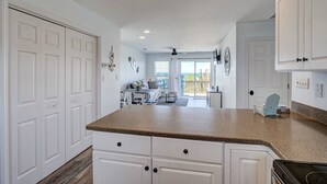 A modern kitchen with white cabinets, a granite countertop, and a view to a balcony. - 3800 Island Drive- Pet Friendly, Direct Oceanfront with Amazing Oceanview's from 2 decks- Adjoini... (North Topsail Beach)