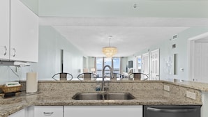 A modern kitchen with granite countertops, stainless steel appliances, and white cabinetry.