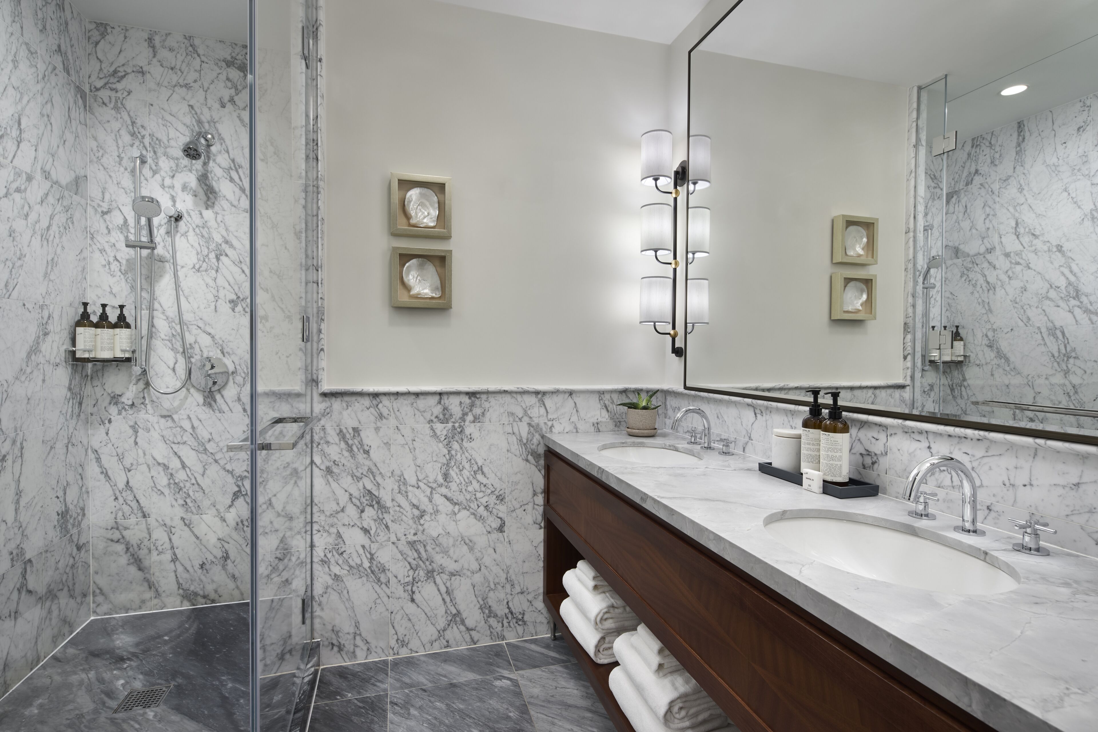 A modern bathroom with a marble shower, a large mirror, and a vanity with a sink.