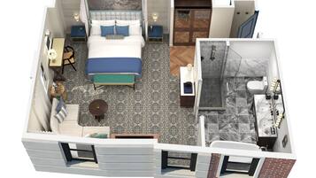 A hotel room with a bed, a desk, a chair, a small table, and a bathroom with a shower and toilet.