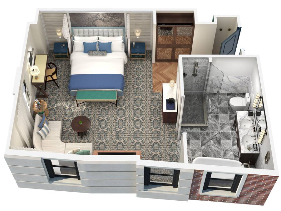 A hotel room with a bed, a desk, a chair, a small table, and a bathroom with a shower and toilet.