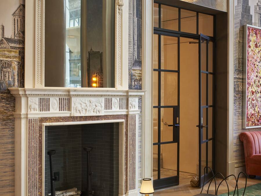 Una habitación con chimenea, una mesa redonda con lámpara y una silla.
