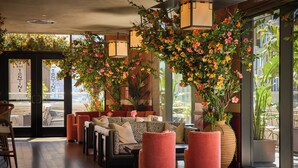 Un moderno espacio lounge con sofá, otomanas y una barra llamada 'Bar Tonine'.