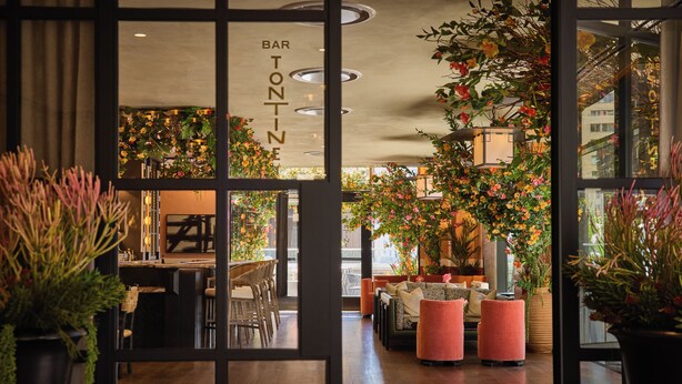 A bar area with a sign reading "BAR TONTINE" and a seating area with pink ottomans and a sofa. - The Wall Street Hotel (New York)