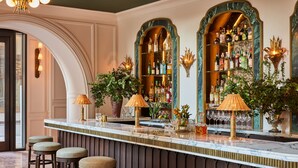 A bar area with marble countertops, stools, and a variety of bottles and glasses. - The Wall Street Hotel (New York)