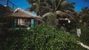 A thatched-roof structure with a pool and lounge area, surrounded by lush greenery and palm trees. - Casa Gaia ~ Mahayana, Private Vacation Home on Tulum beach with turquoise sea at your doorstep! (Tulum)