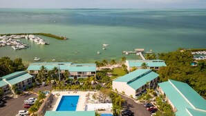 A resort with a swimming pool, multiple buildings, and a marina with boats.
