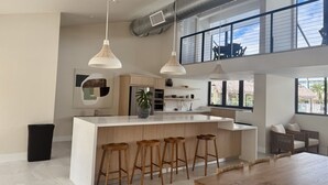 A modern kitchen with a central island, bar stools, pendant lighting, and a view of the outdoors.