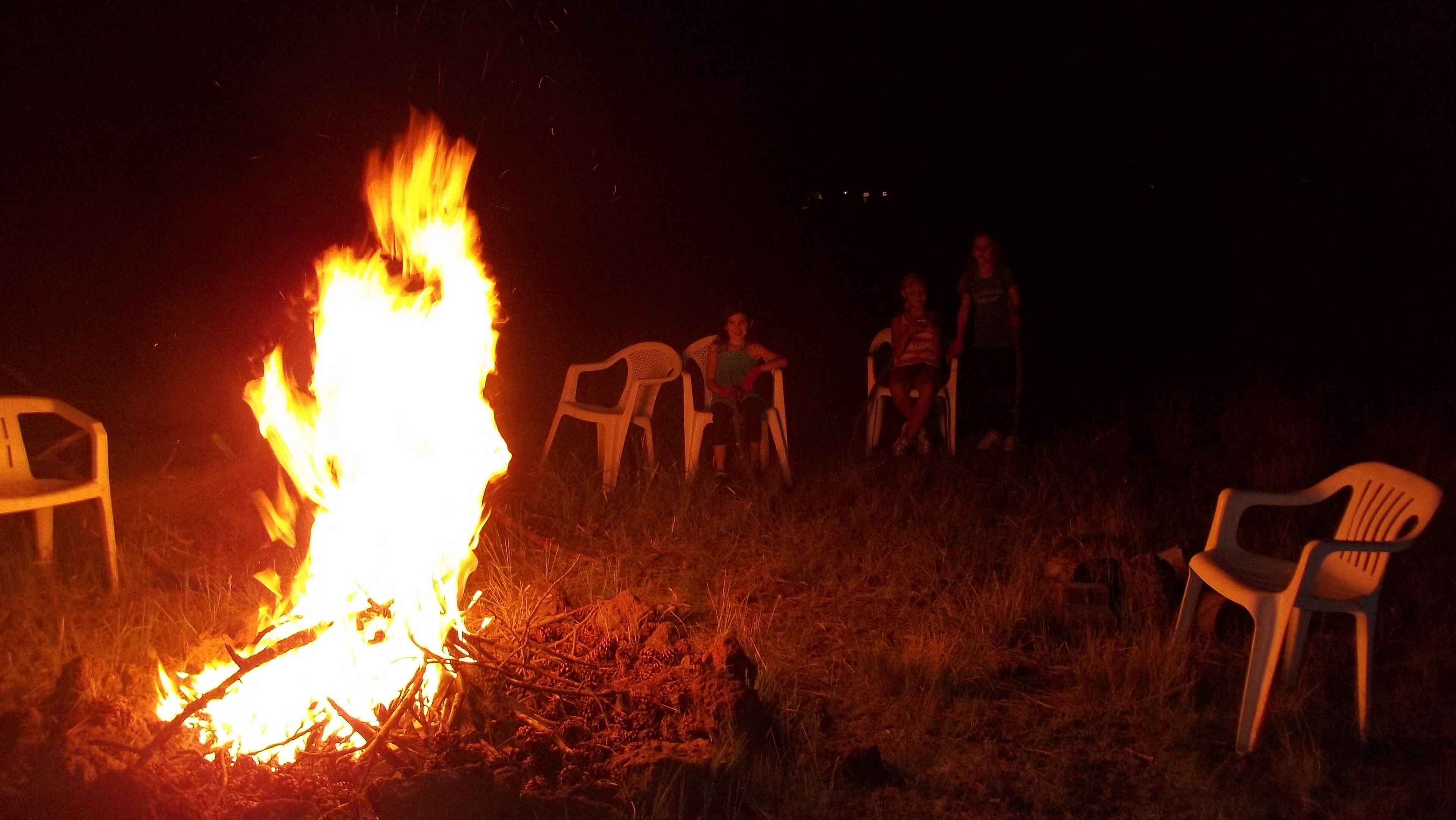 Ein Lagerfeuer mit Plastikstühlen darum herum.