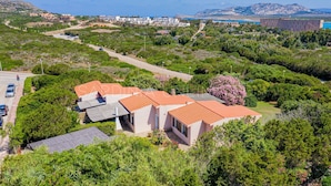 Et kystnært boligområde med huse, en vej og et bjerg i baggrunden.