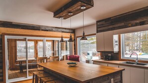 A modern kitchen with wooden countertops, a central island, and pendant lighting. - Le 2800 du Parc (Shawinigan)