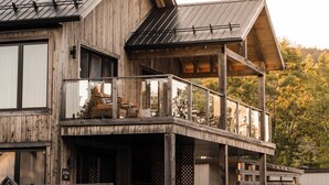 A wooden house with a balcony, a chimney, and a deck area. - Le 2800 du Parc (Shawinigan)