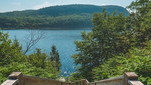 A wooden staircase leading to a lake with a forested hill in the background. - Le 2800 du Parc (Shawinigan)