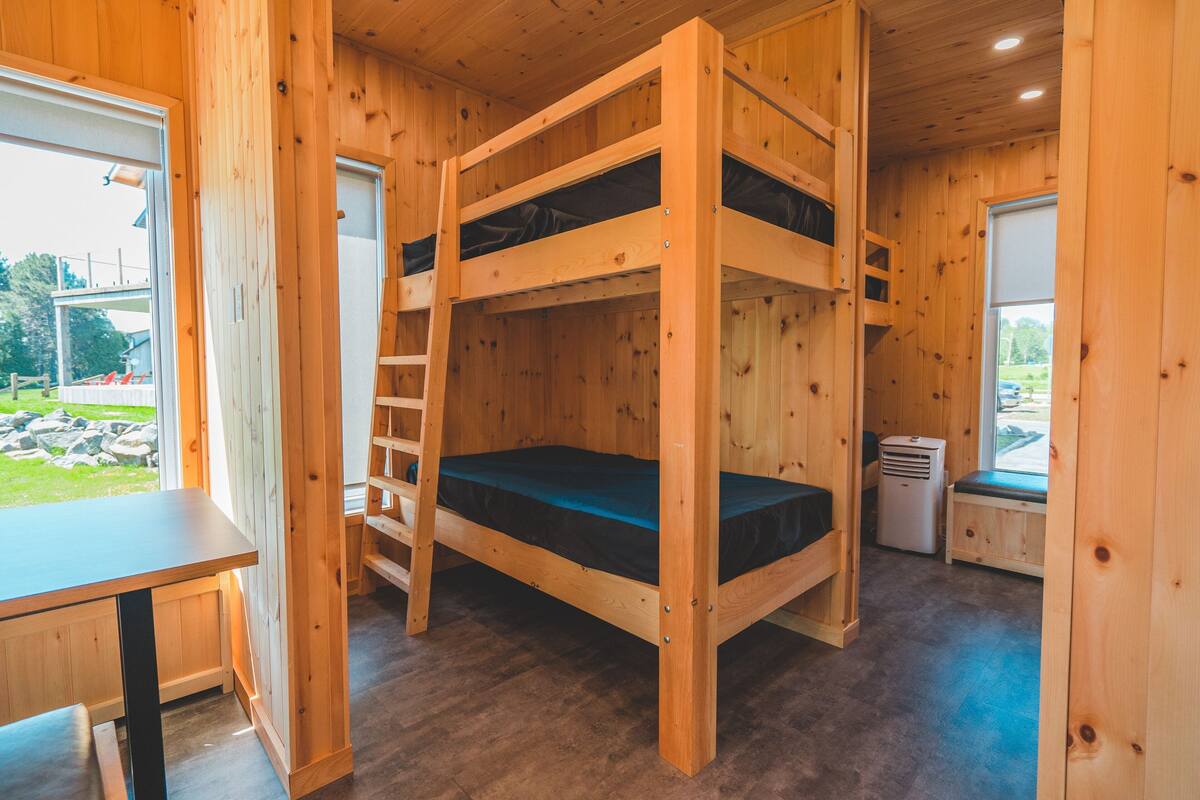 Quarto com beliche, mesa e janela.