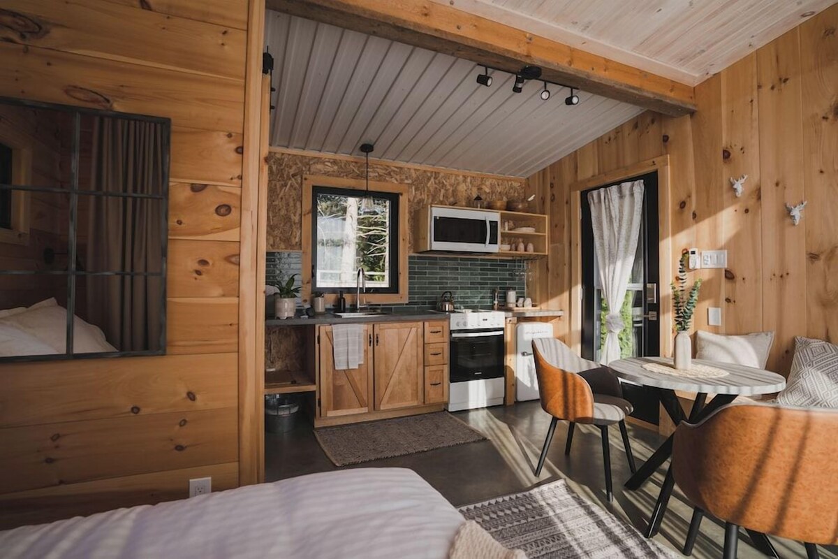 A compact wooden cabin with a kitchenette, a dining area, and a sleeping area.