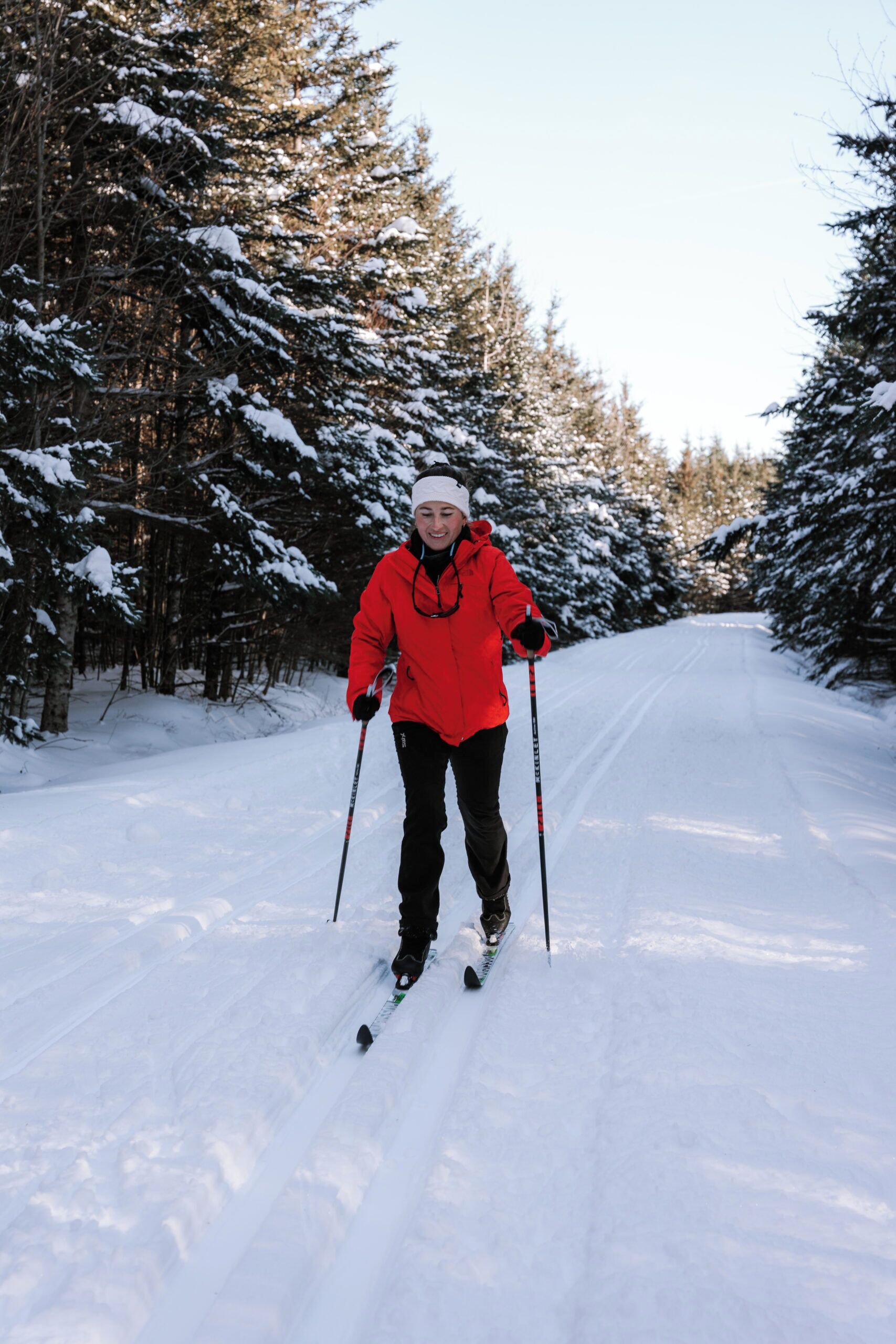 Una persona practica esquí de fondo sobre un sendero cubierto de nieve, rodeada de árboles.