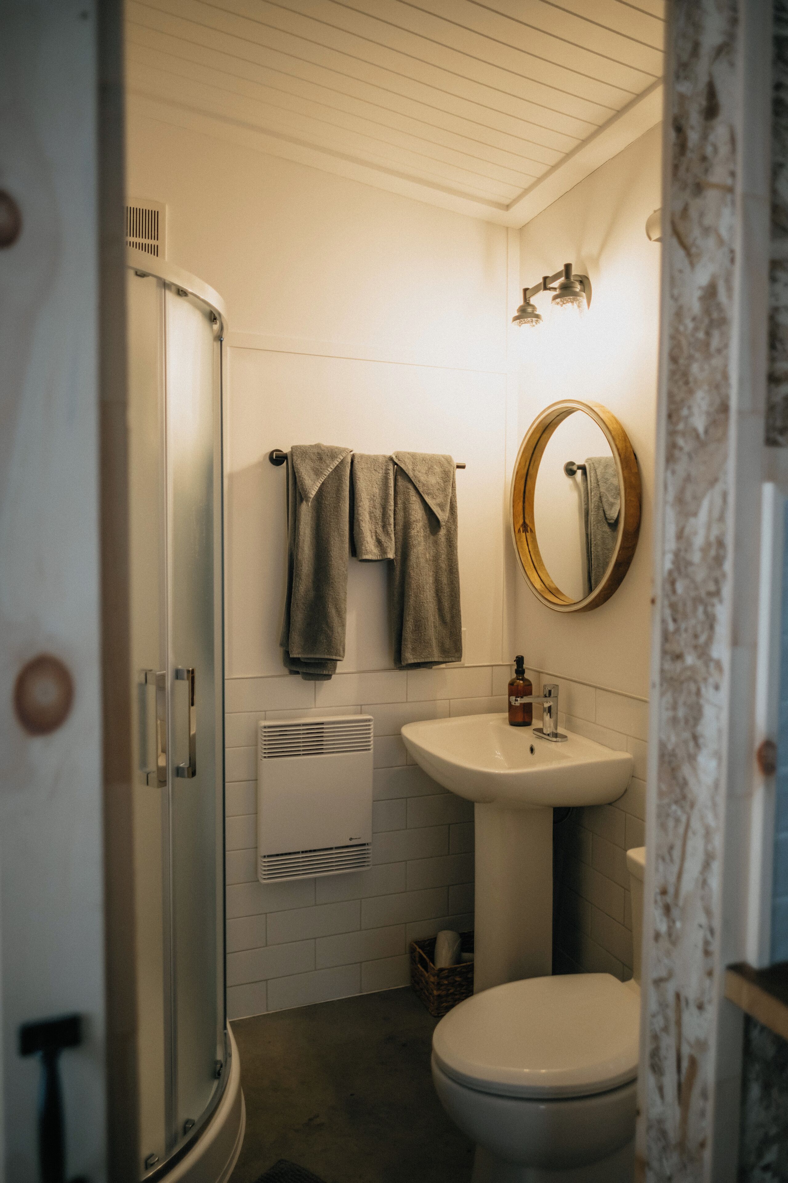 Et badeværelse med bruser, vask, toilet og spejl.