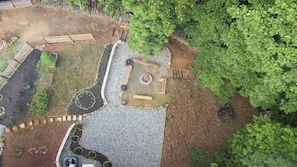Vista aérea de una zona ajardinada con un sendero de grava, un parterre circular y un pequeño hogar para fuego.