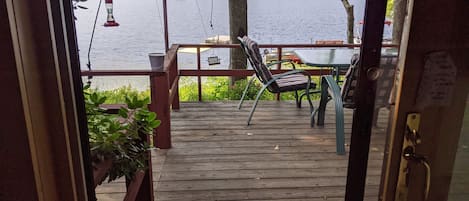Um deck de madeira com mesa e cadeiras, com vista para um lago.