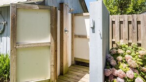 A wooden outdoor shower with a metal door, a wooden deck, and a wooden fence.