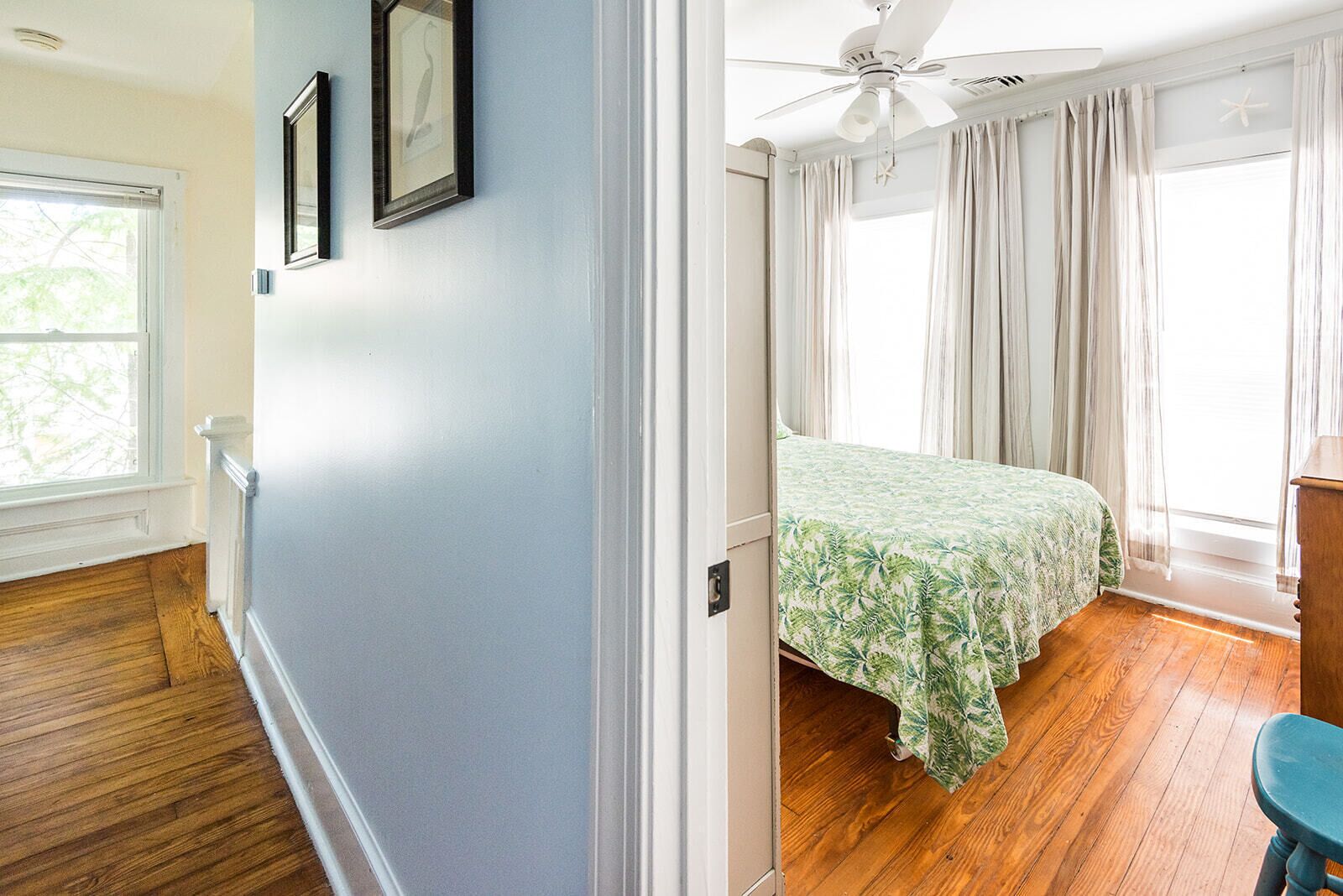 A bedroom with a bed, a ceiling fan, and a window with curtains.