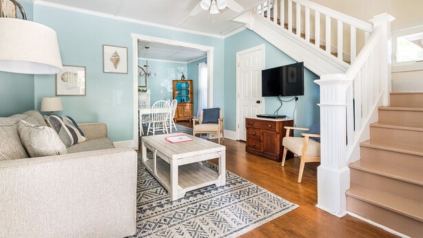 A living room with a sofa, coffee table, and a staircase leading to another level.