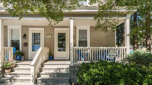 A two-story house with a porch, a welcome sign, and a small garden area.